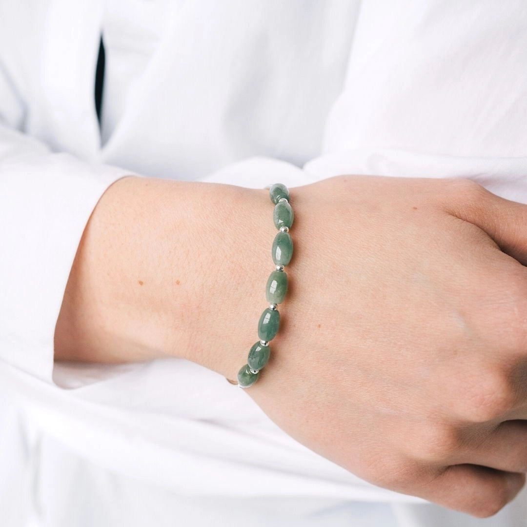 Green jade silver bracelet featuring a natural oval stone, elegantly worn on a person's wrist.