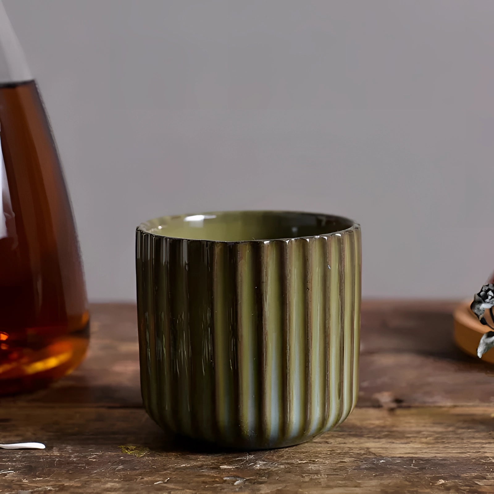 Handmade artisan green ribbed ceramic mug in Design C, with a 180ml capacity, sitting on a wooden surface.