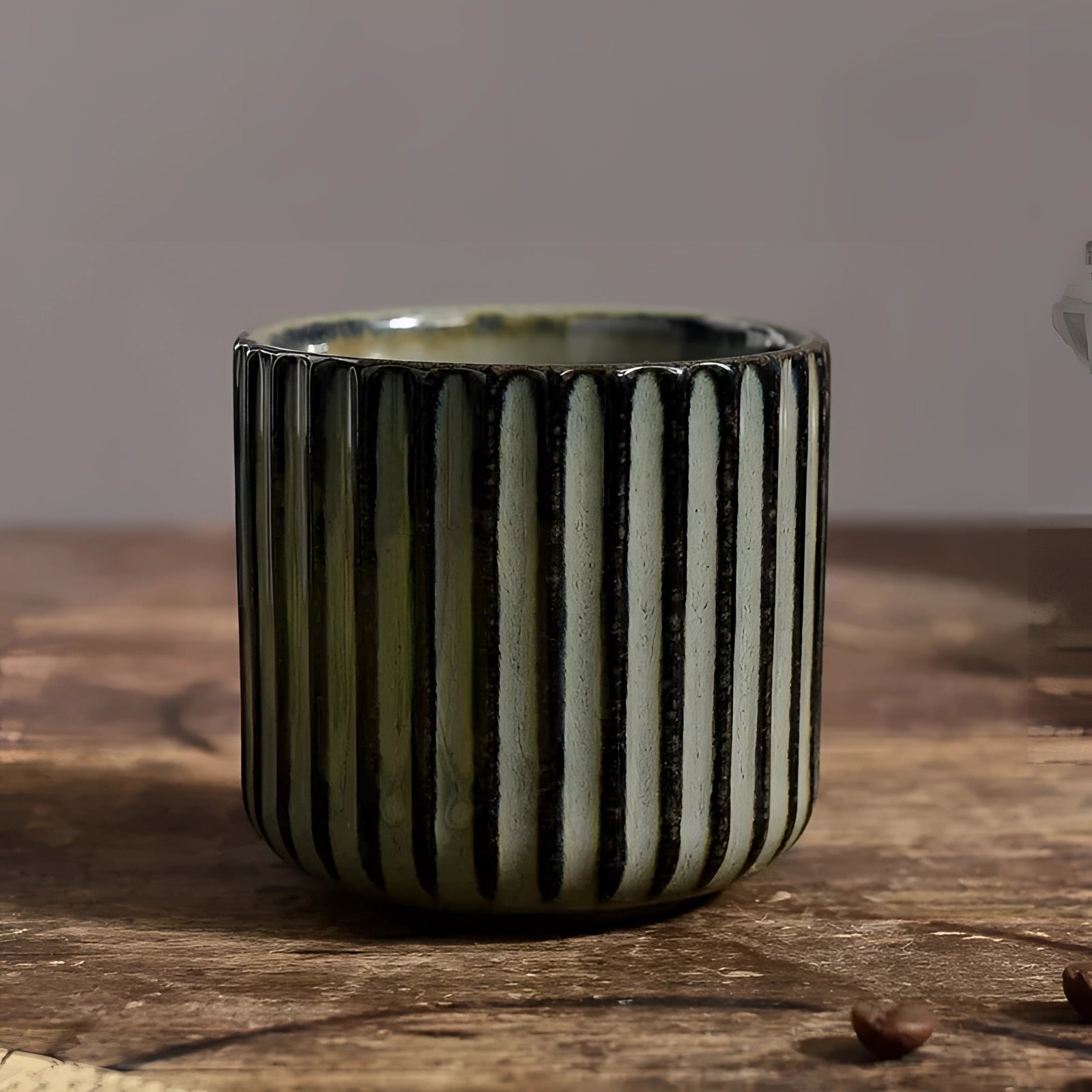 Handmade artisan stoneware mug with a green ribbed design, 180ml capacity, displayed on a wooden surface.