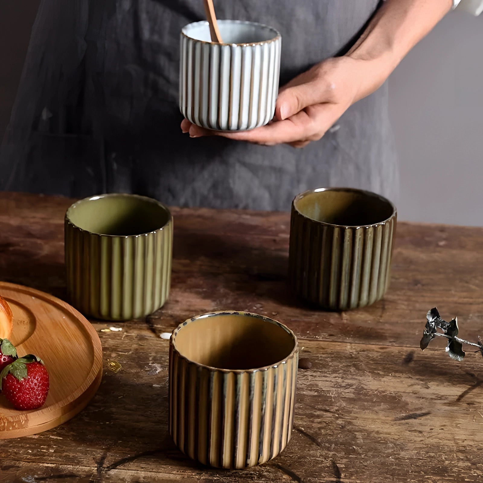 Handmade artisan stoneware green ribbed ceramic mug placed on a wooden table.