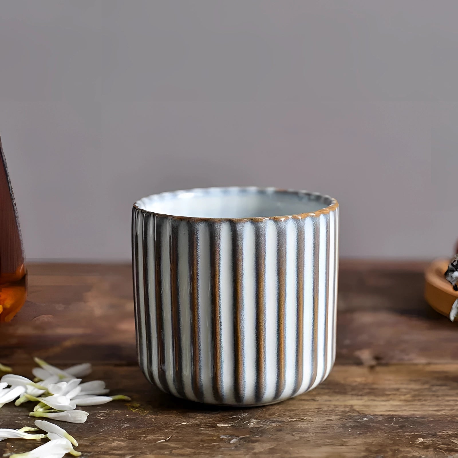 Handmade artisan stoneware mug in a ribbed green ceramic design, with a capacity of 180ml, placed on a wooden table.