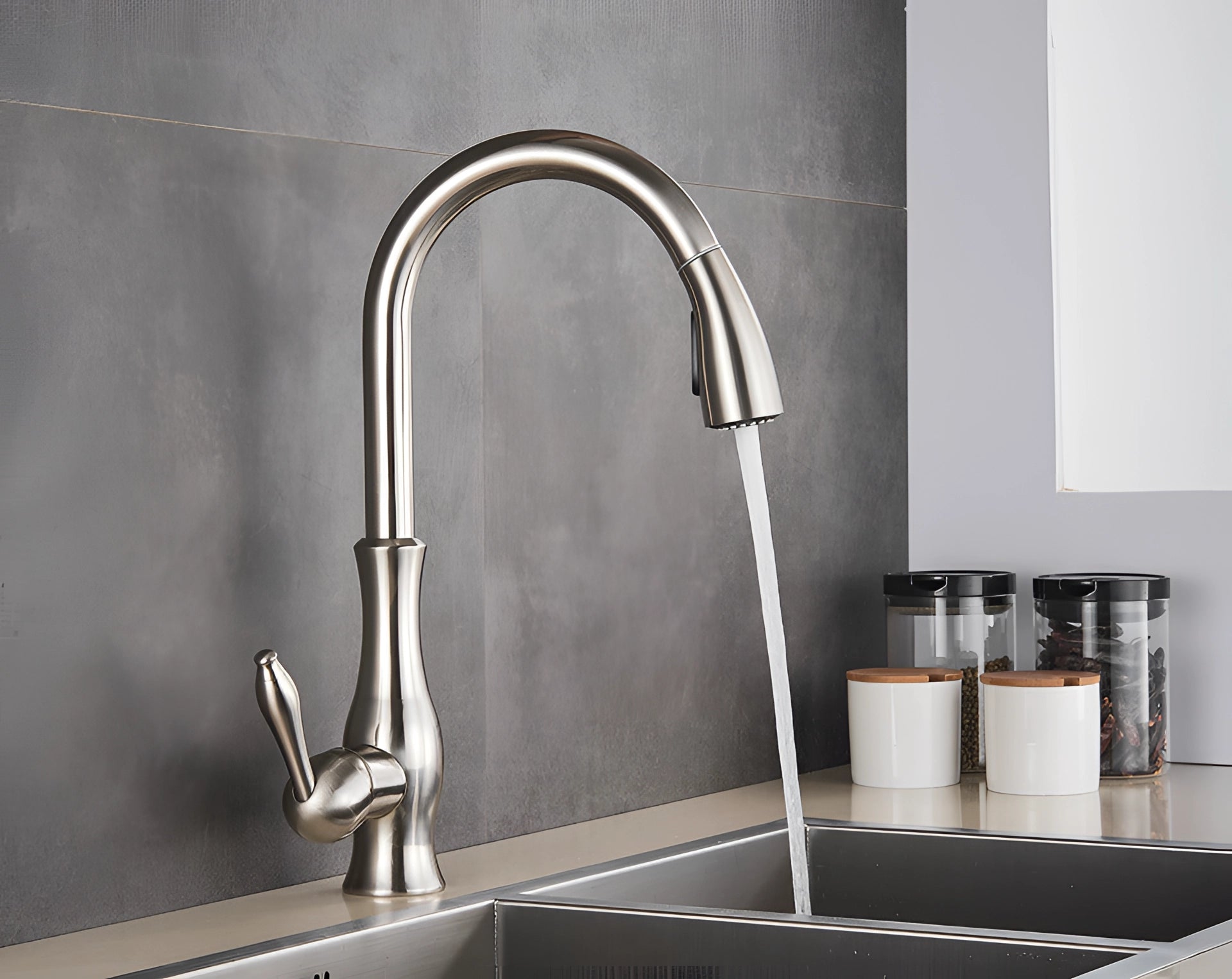 High-arc brushed nickel stainless steel pull-down kitchen faucet installed on a sleek grey countertop with a rectangular sink, showcasing modern interior design and functional household hardware.