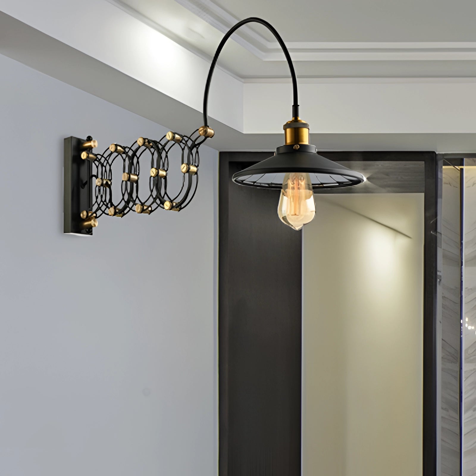 Industrial antique brass adjustable wall sconce with an Edison bulb, featuring a black finish and mounted on a wooden wall backdrop.