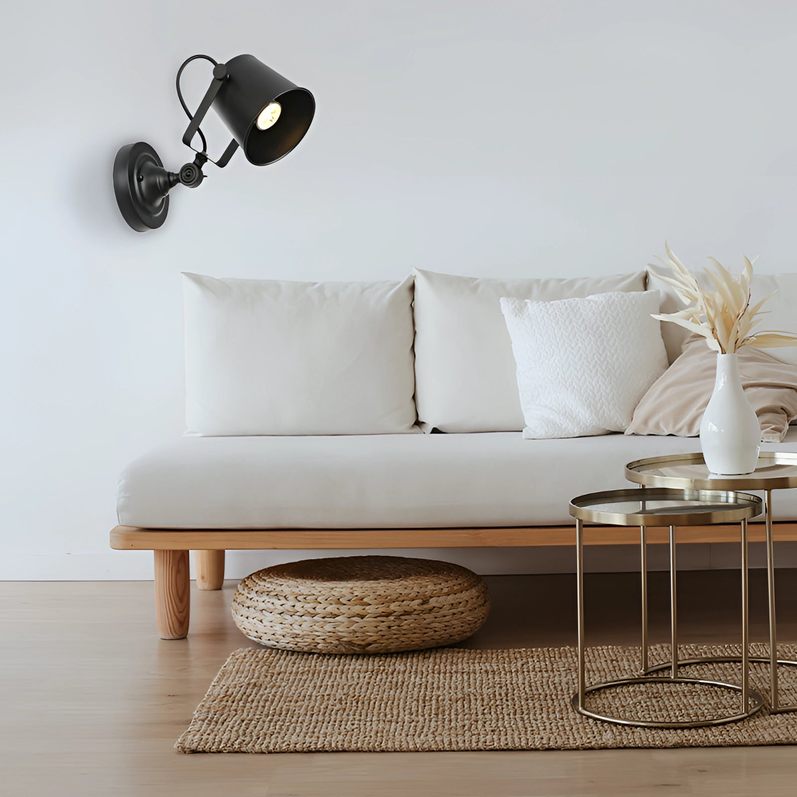 Industrial black metal wall lamp with an adjustable arm, designed for LED compatibility. The lamp is mounted on a wall above a grey studio couch, adding a touch of modern elegance to the interior design.