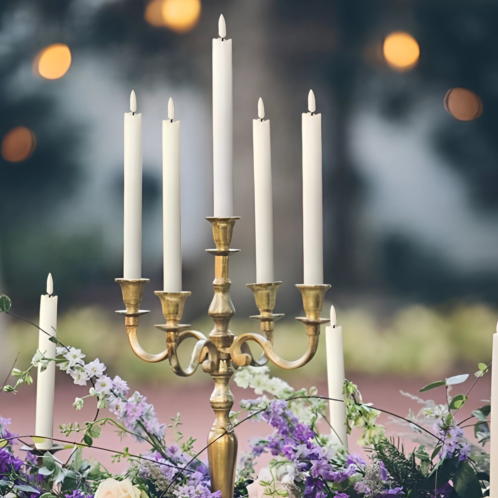 LED flameless flickering taper candles displayed in an elegant setting with candle holders, surrounded by decorative flowers and petals, creating a warm and inviting atmosphere.