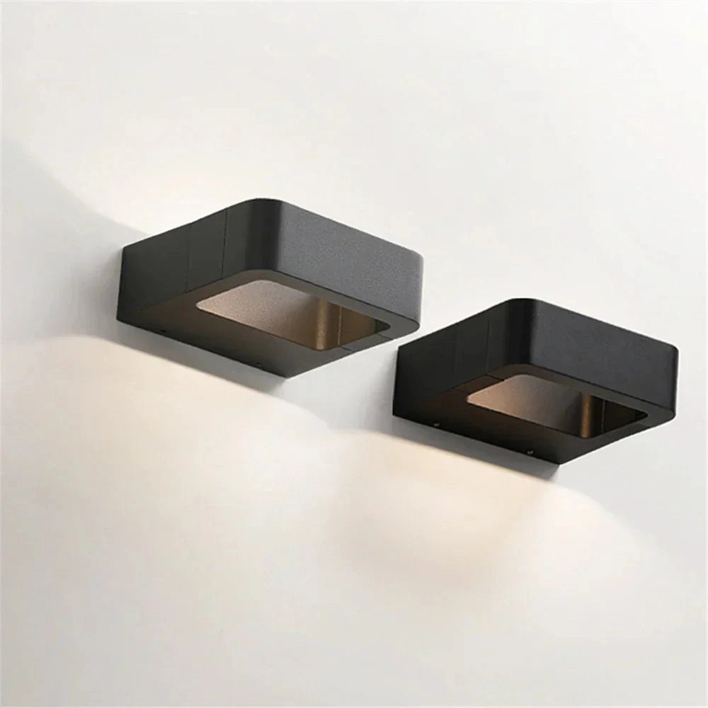 Modern gray rectangular LED wall sconce with a weather-resistant design, featuring a cool light, mounted on an exterior wall with wood paneling.