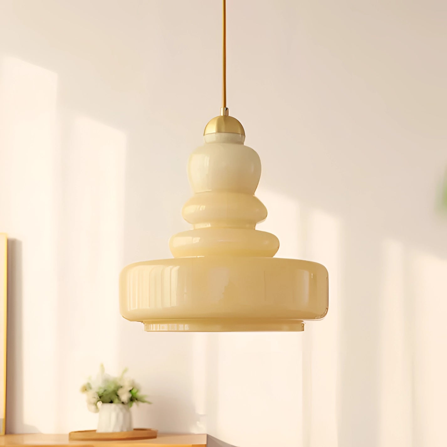 Lime green modern pendant light with a Scandinavian tiered design, hanging above a kitchen table; beige yellow glass and iron construction, surrounded by houseplants and wooden elements.