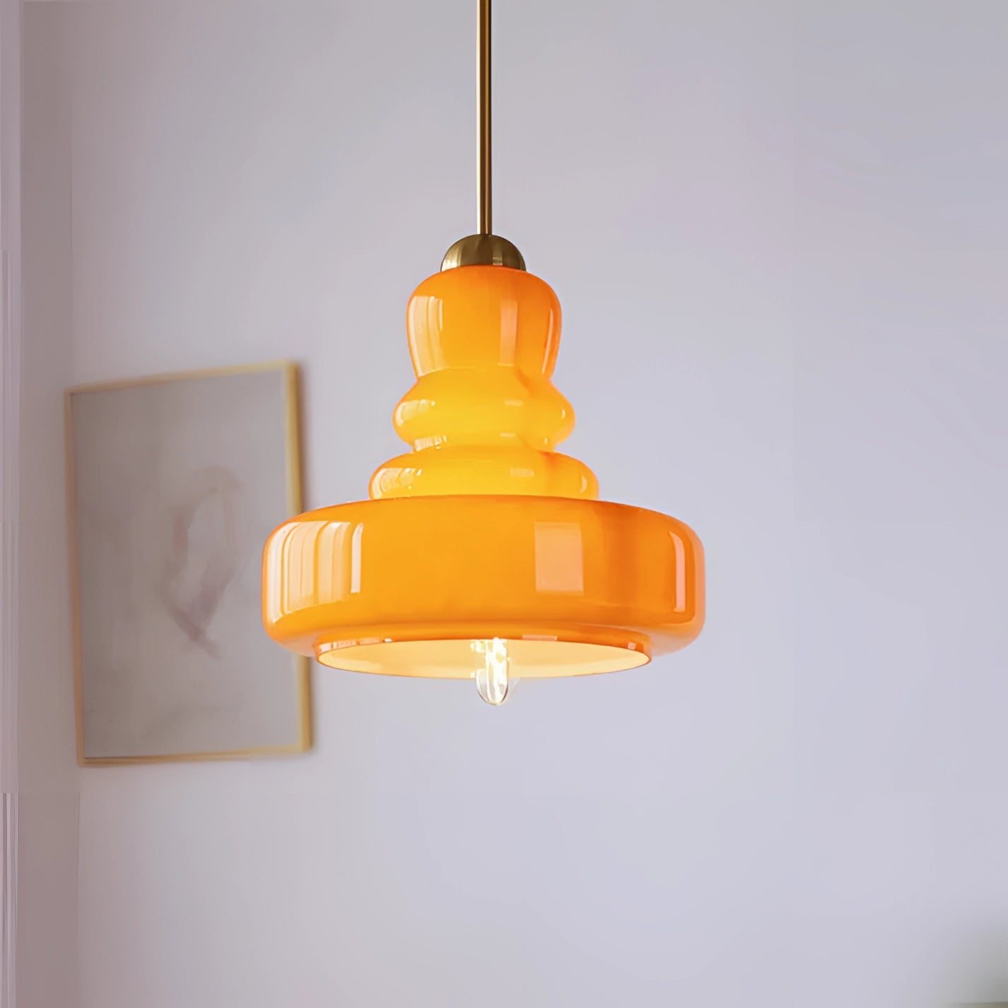 Lime green and orange modern pendant light with a Scandinavian tiered design made of glass and iron, hanging from the ceiling.