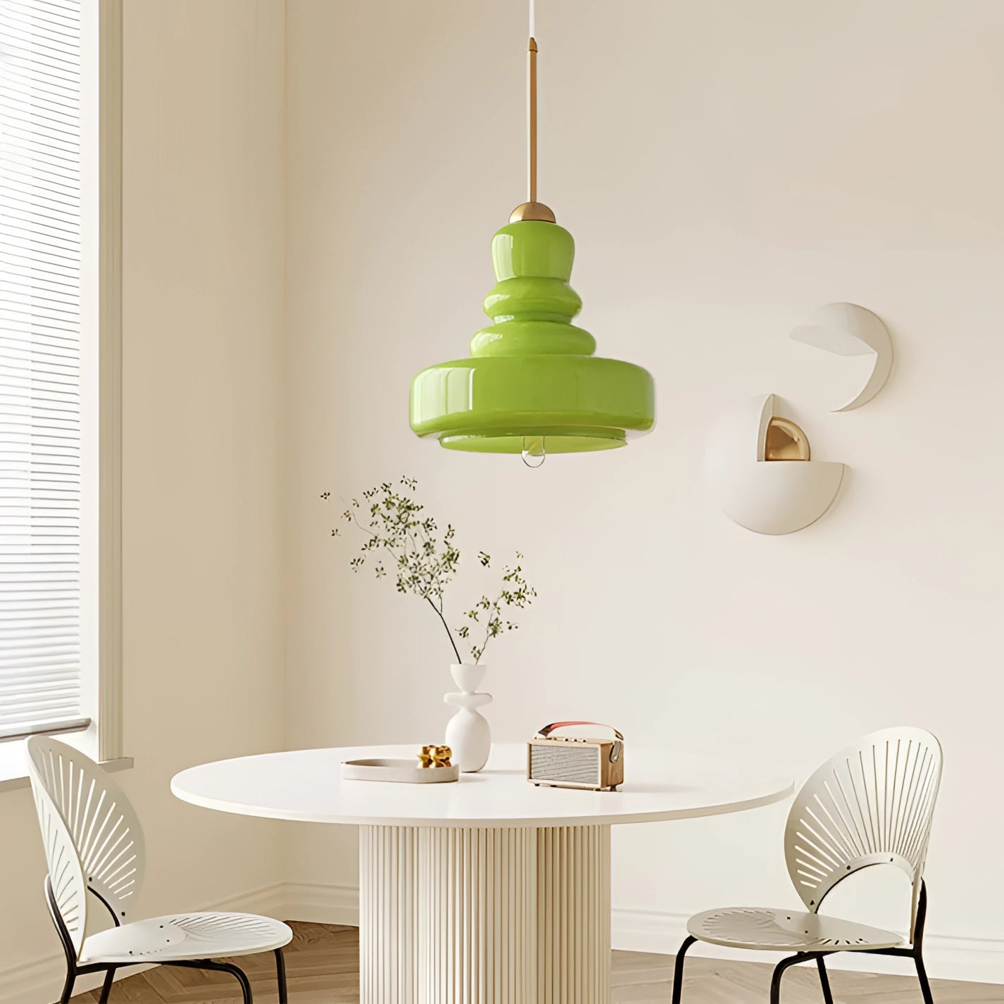 Lime green modern pendant light in Scandinavian design hanging over a wooden dining table with white chairs and dishware in a stylish kitchen interior.