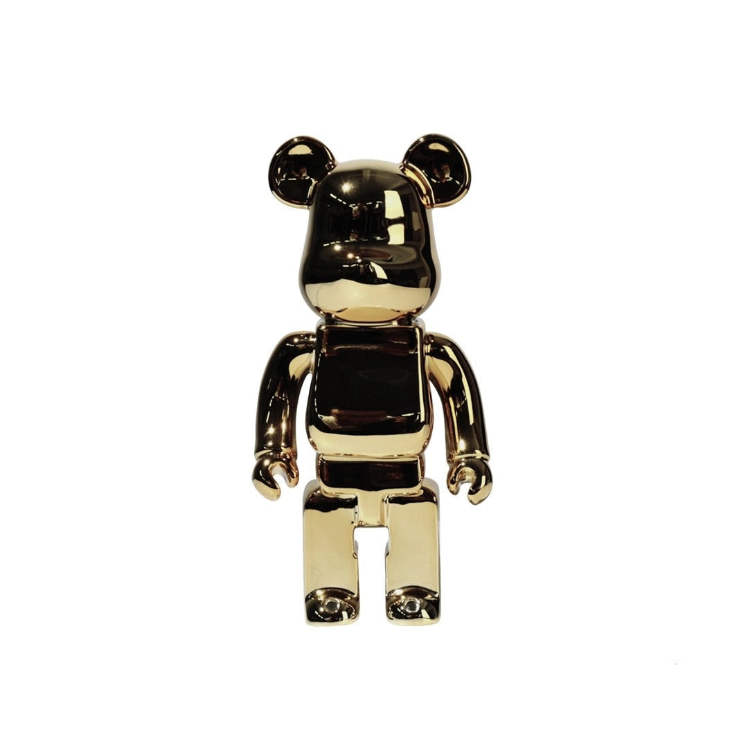 Clear vinyl bearbrick designer art toy figurine in gold color, showcasing a stylized bear with a metallic finish, featuring a playful gesture.