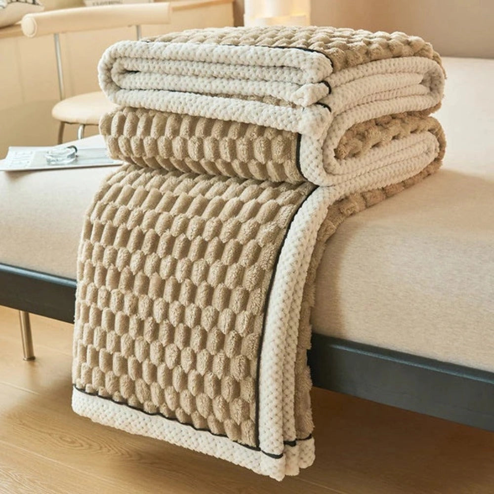 Luxurious Pink Blush Throw Blanket in Latte color with a soft plush fleece texture featuring a zigzag pattern, draped over a beige outdoor chair on a wooden floor.