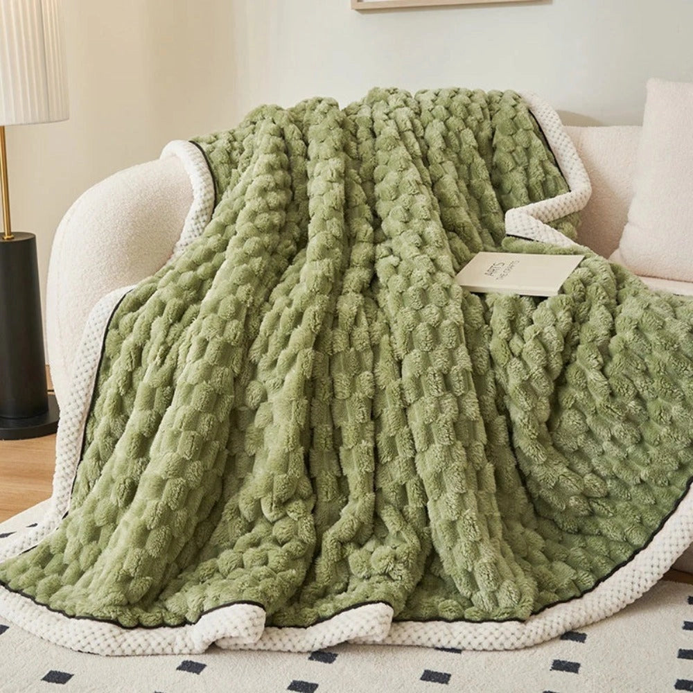 Luxurious pink blush throw blanket with a soft plush fleece texture and a zigzag pattern draped over a wooden floor.