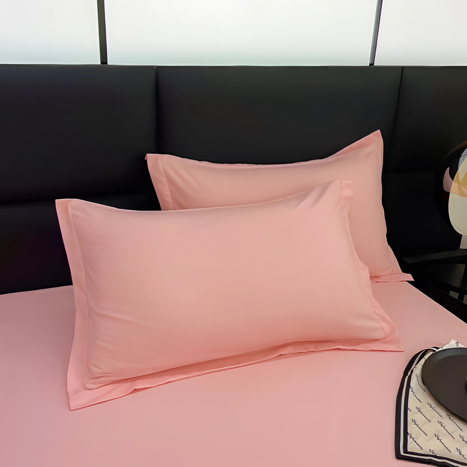 Blush pink silk pillowcase on a neatly made bed with wooden bed frame, featuring a rectangular shape and smooth texture, designed to be hypoallergenic and gentle on hair.