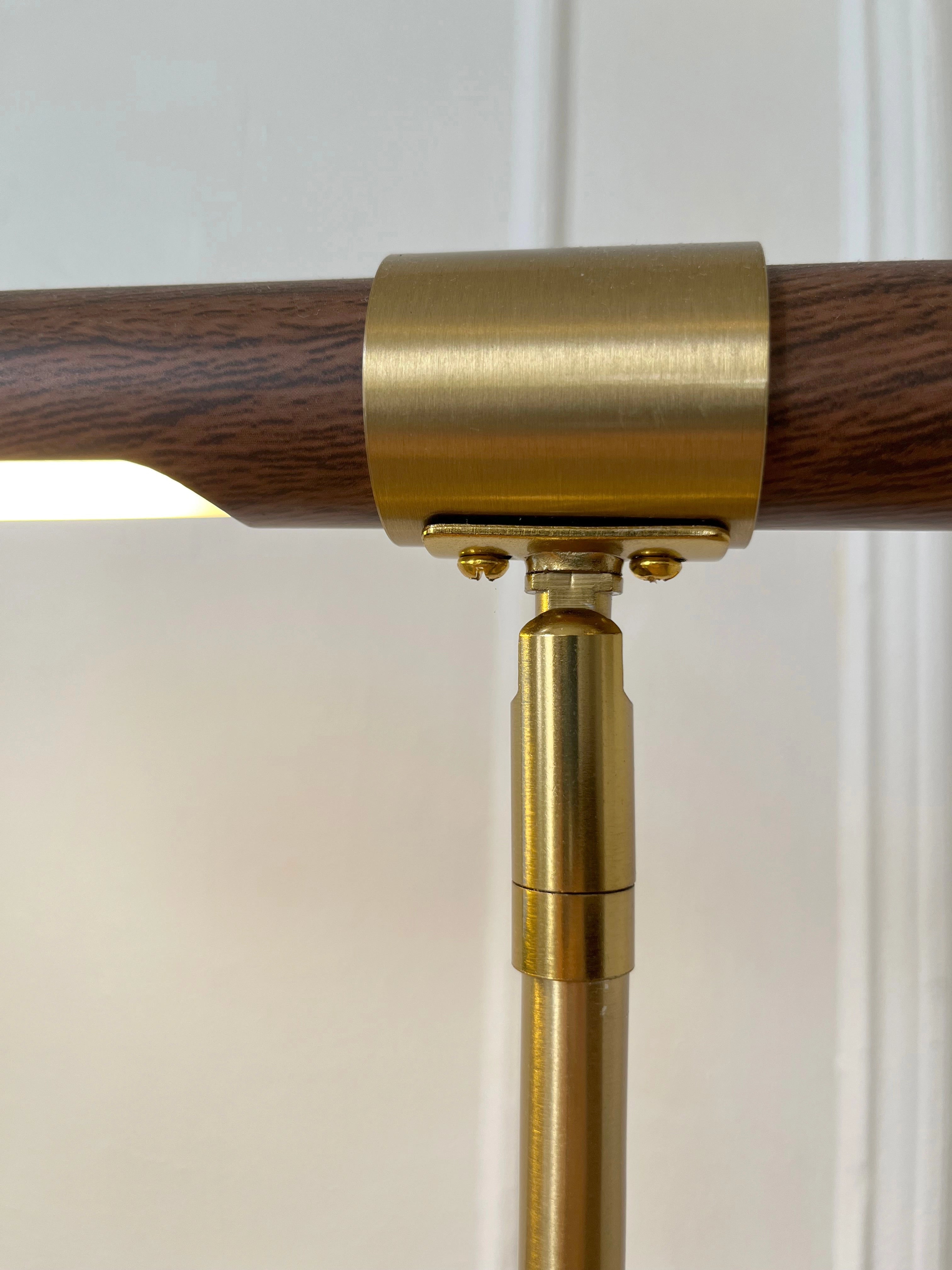 Luxury brass and wood adjustable desk lamp with modern design, featuring a rectangular wooden base, brass fittings, and a cylindrical glass shade.