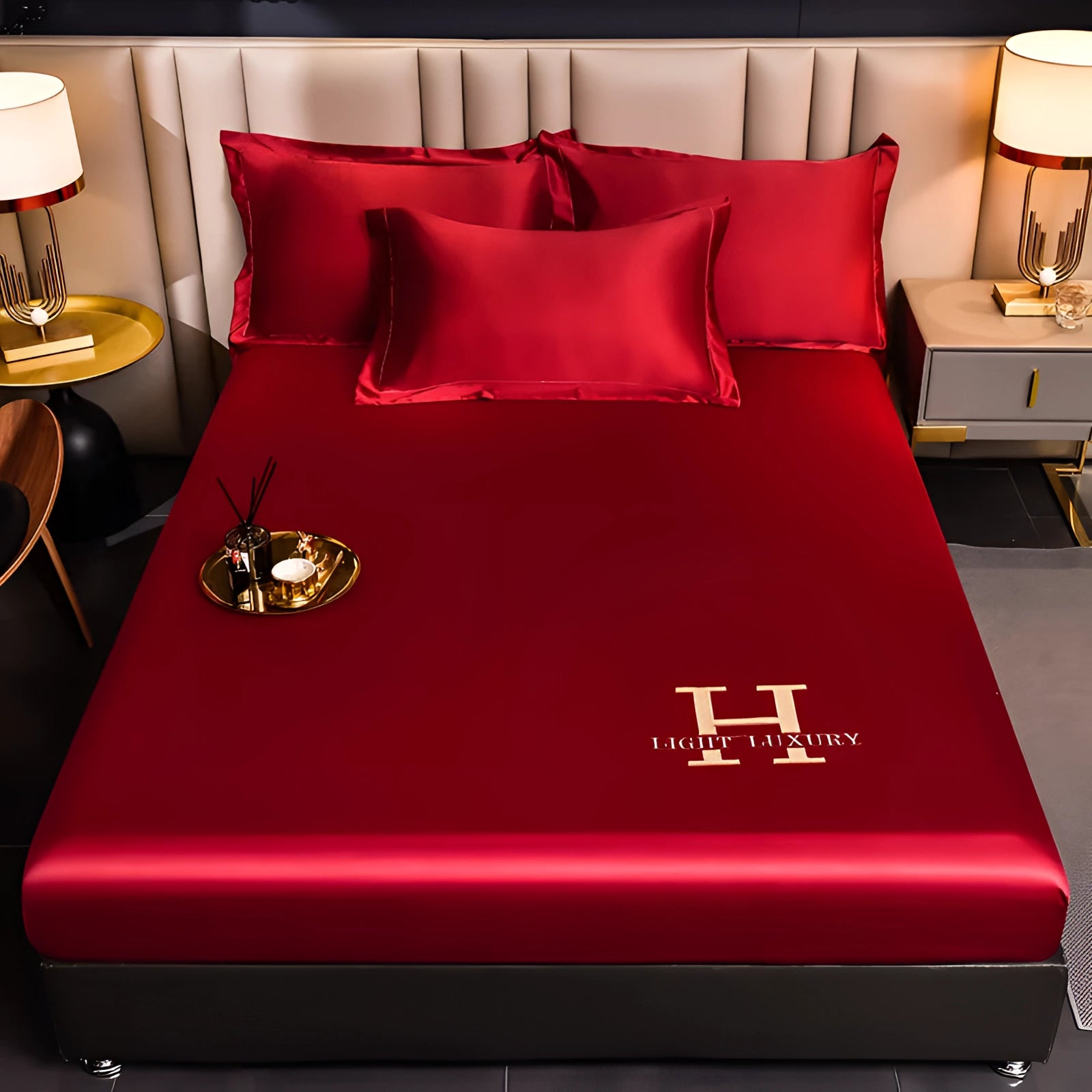 Luxurious burgundy silk bedding set on a neatly made bed, featuring premium satin sheets and pillowcases in a rich red hue. The bedding's elegant sheen enhances the overall aesthetics of the room, which is softly lit to create a warm and inviting atmosphere. The bed is dressed with multiple satin pillows that complement the luxurious fabric, set against a backdrop of a tastefully designed interior. A touch of wood furniture can be seen, adding to the room's sophisticated decor.