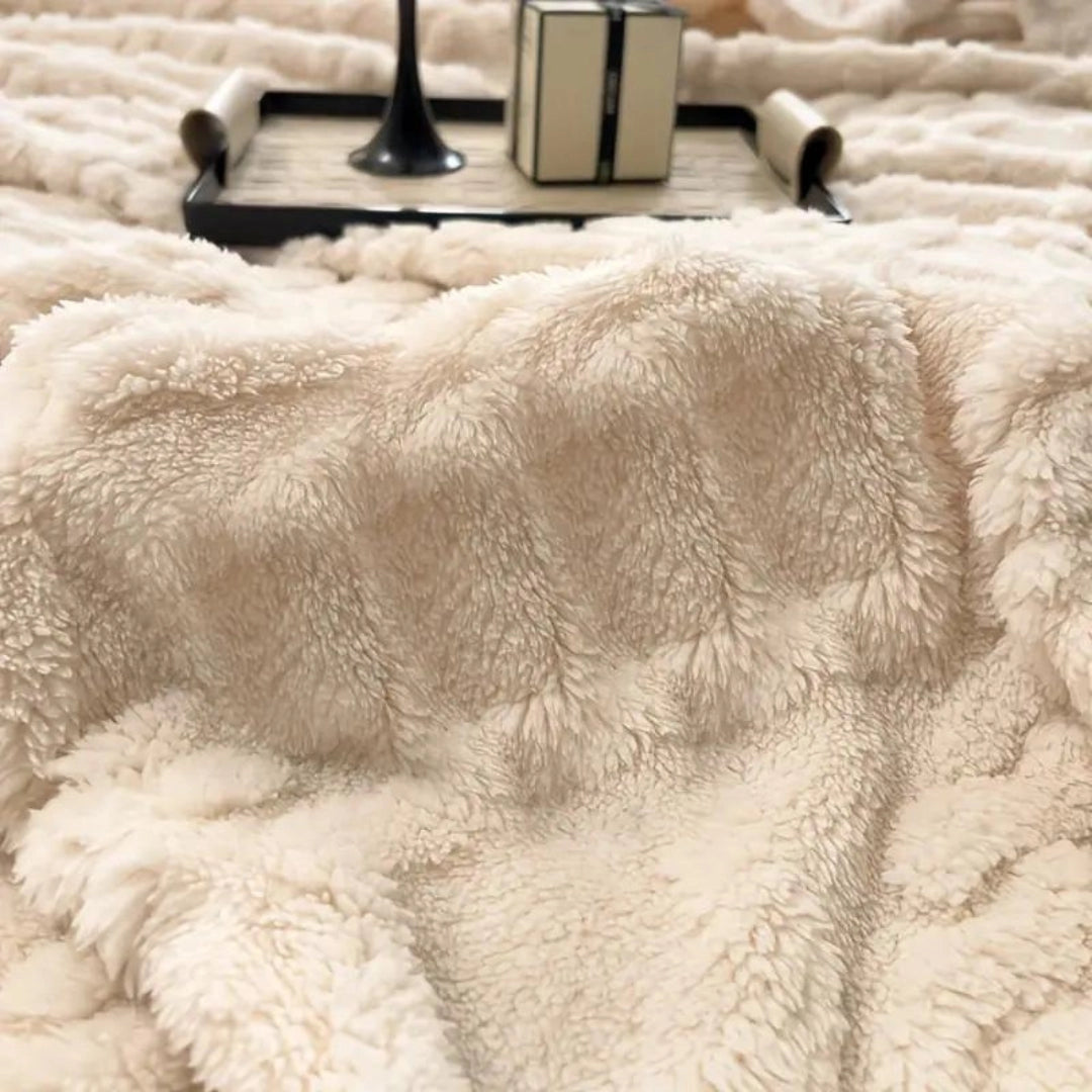 Elegant cream luxury cable knit throw blanket draped gracefully on a soft surface, showcasing its cozy and high-quality craftsmanship.