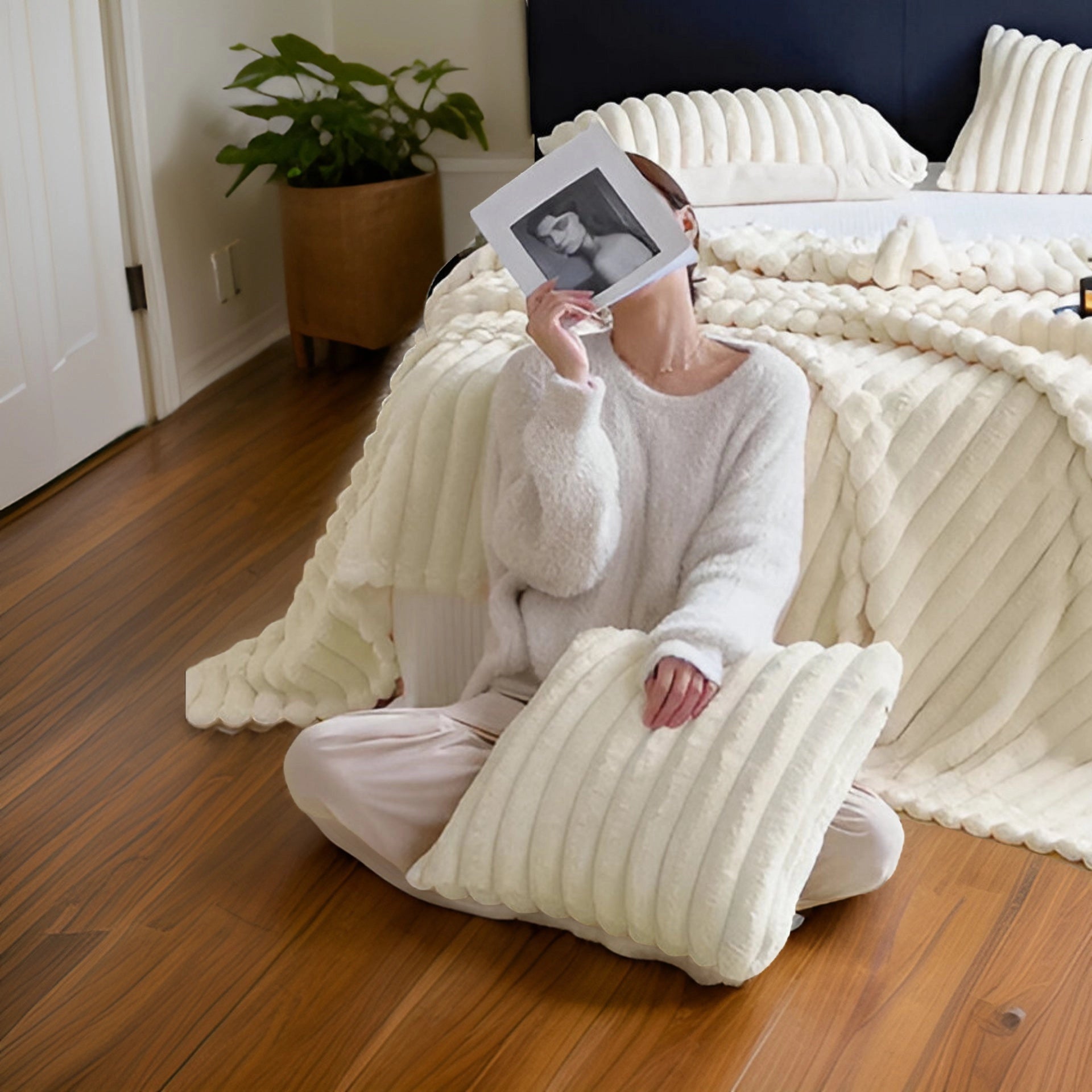 Luxury chunky knit blanket draped over a modern couch with hardwood flooring and a houseplant in the background.