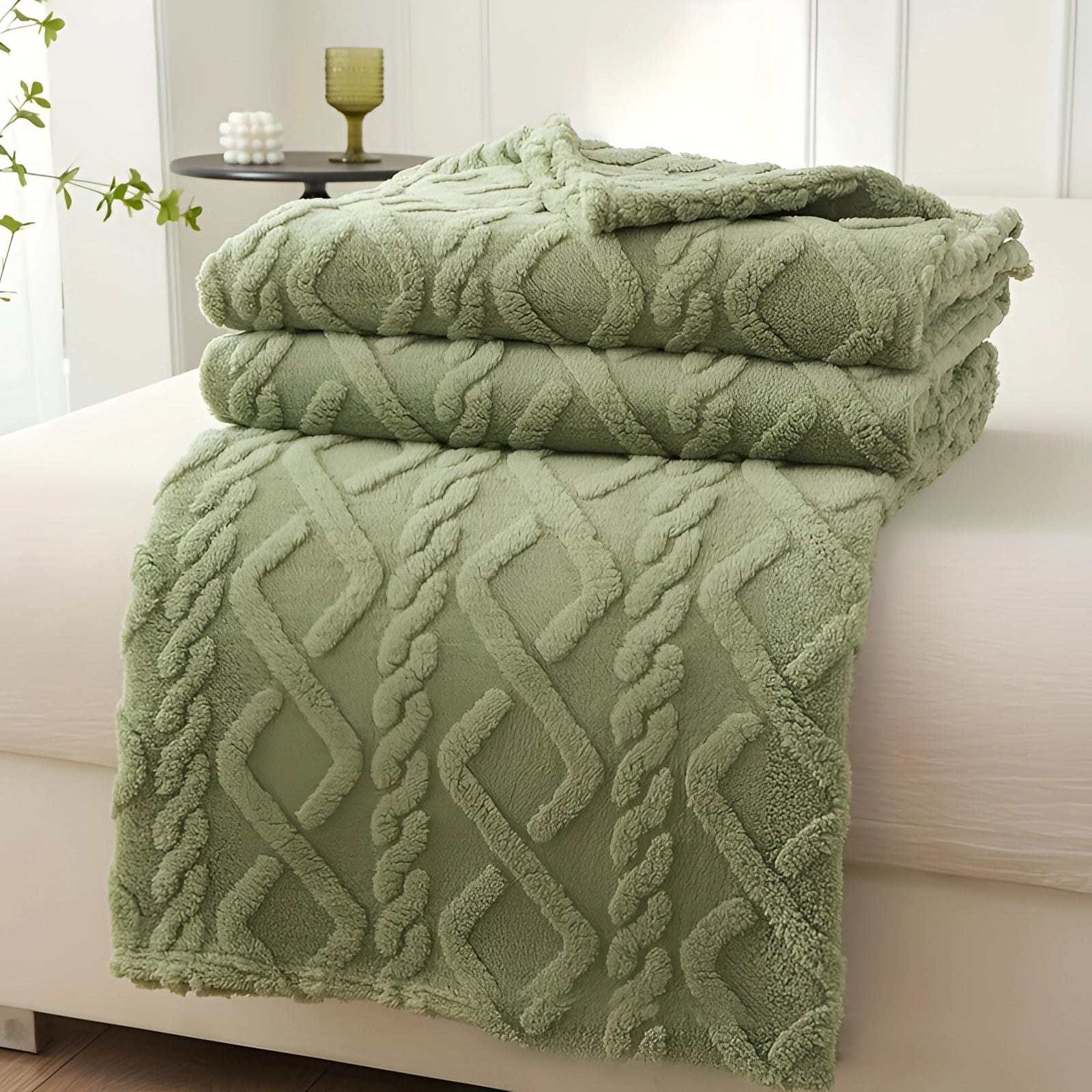 Luxurious cream geometric throw blanket draped over a plush green armchair, measuring 175 x 195 cm, providing a cozy and comfortable accent. The setting features wooden flooring and neutral-toned furniture, creating an inviting and stylish living space.