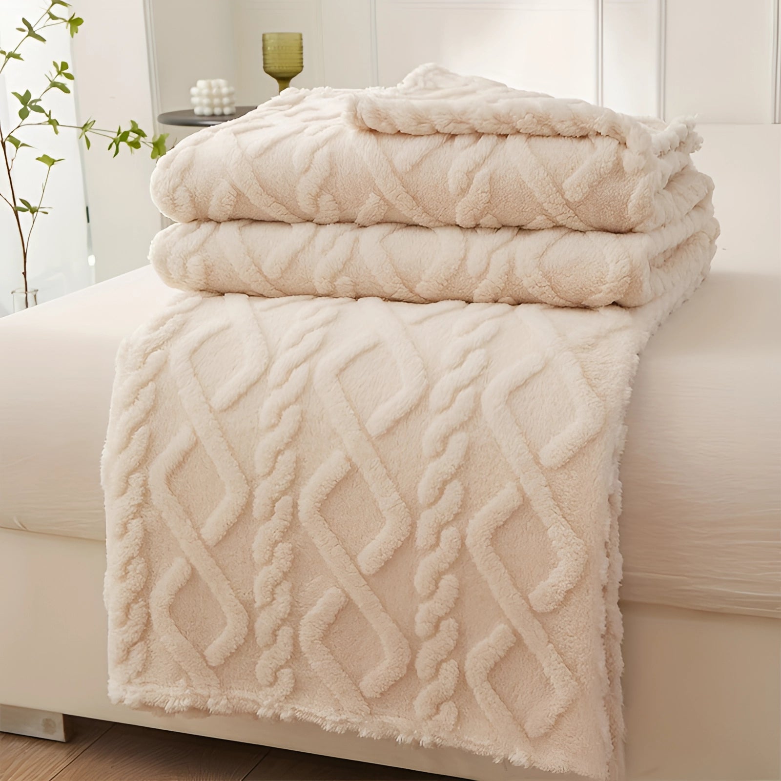 Luxury cream geometric throw blanket in a plush texture, draped over an armchair. The blanket is in a soft khaki color and measures 175 x 195cm. It adds a touch of elegance and comfort to a room with wooden flooring and a beige color scheme.