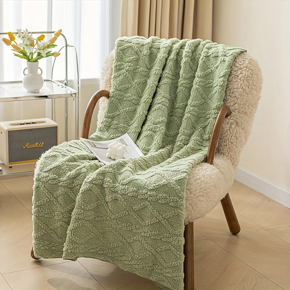 Luxury cream geometric throw blanket draped over a plush armchair in a stylish interior setting, with a wooden floor, potted plant, and a yellow floral arrangement adding warmth and comfort to the room.