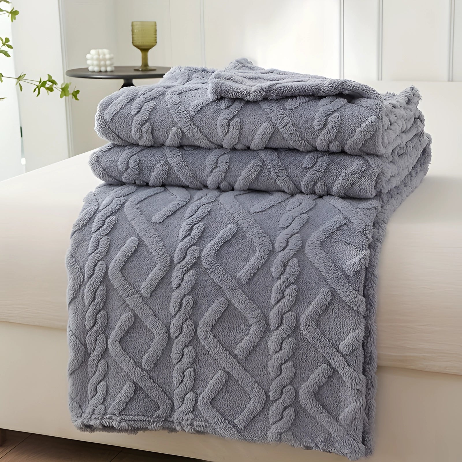 Plush blue and cream geometric throw blanket draped over a grey armchair, set in a room with hardwood flooring.