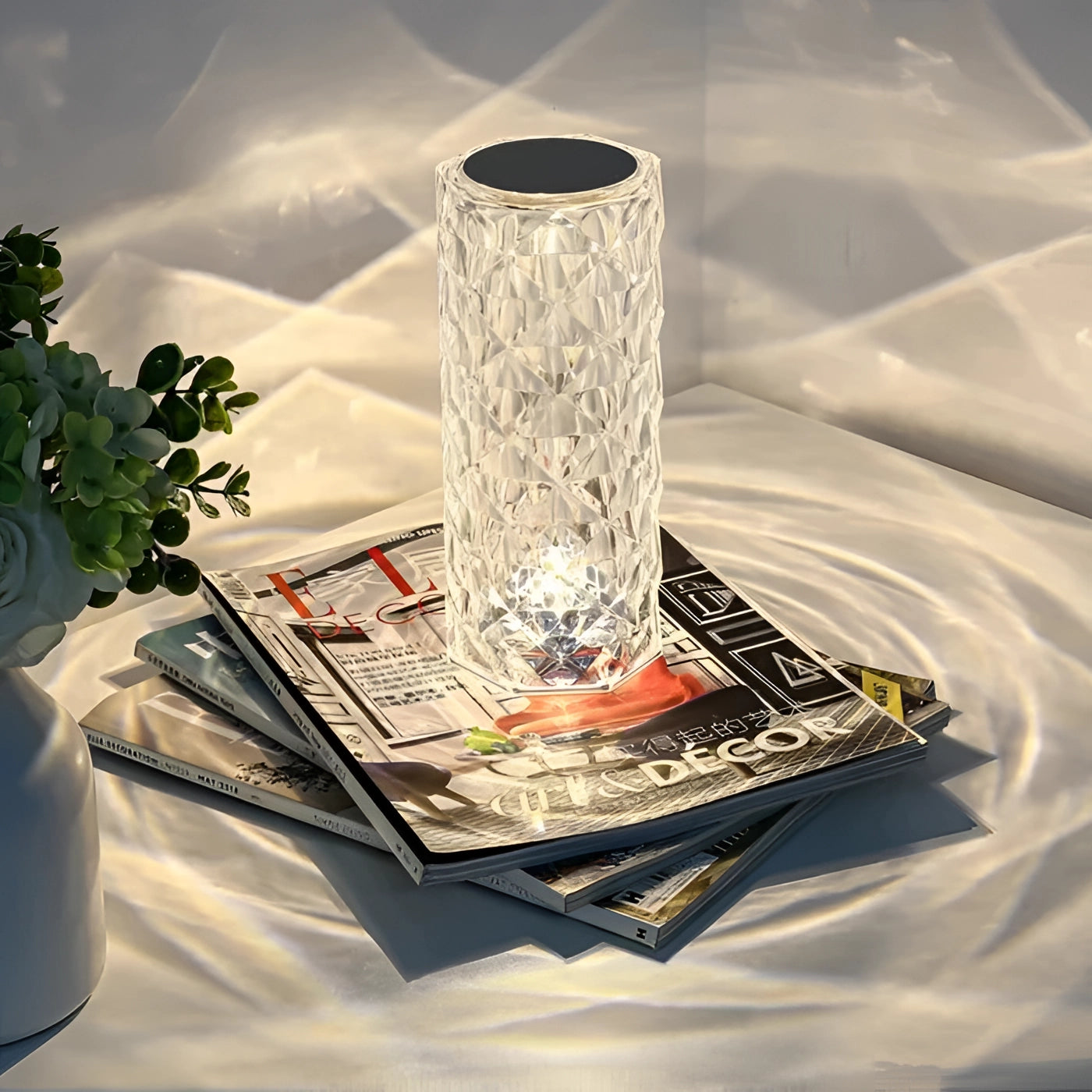 A luxury crystal vase with an elegant cylindrical design, perfect as a centerpiece or premium decor item, showcased on a table with plant and flower arranging elements.