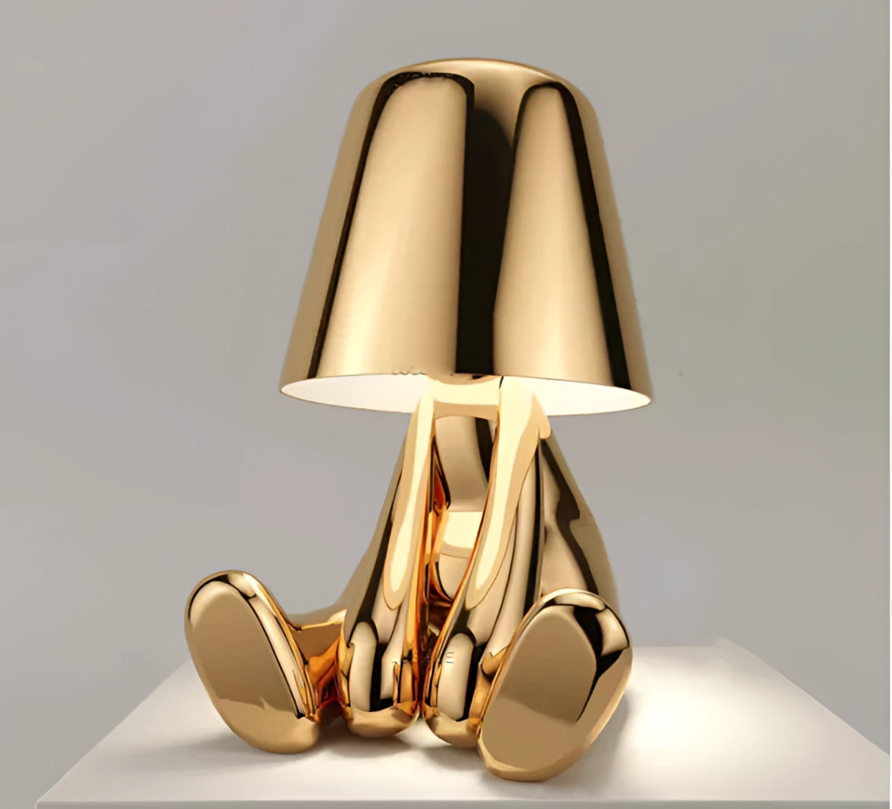 Luxury gold finish sculptural table lamp with a rectangular base, featuring a sleek metal and wood design, complemented by an artful lampshade.