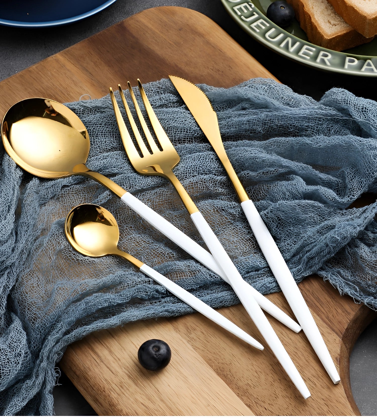 Luxury gold cutlery set displayed on a wooden surface, showcasing elegant tableware with a modern design featuring metallic gold utensils.