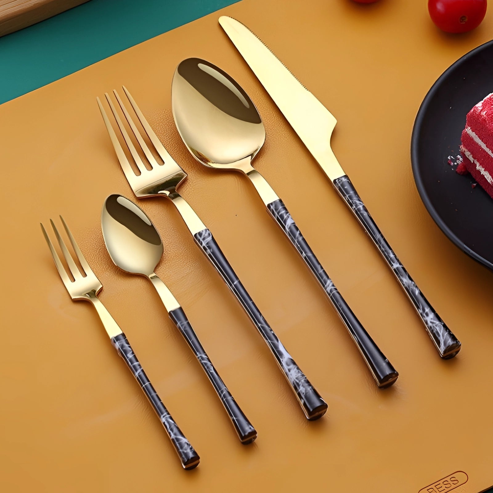 Luxury gold marble handle cutlery set displayed on a wooden table, featuring a fork alongside other tableware and dishware, with a rectangular plate in the background.