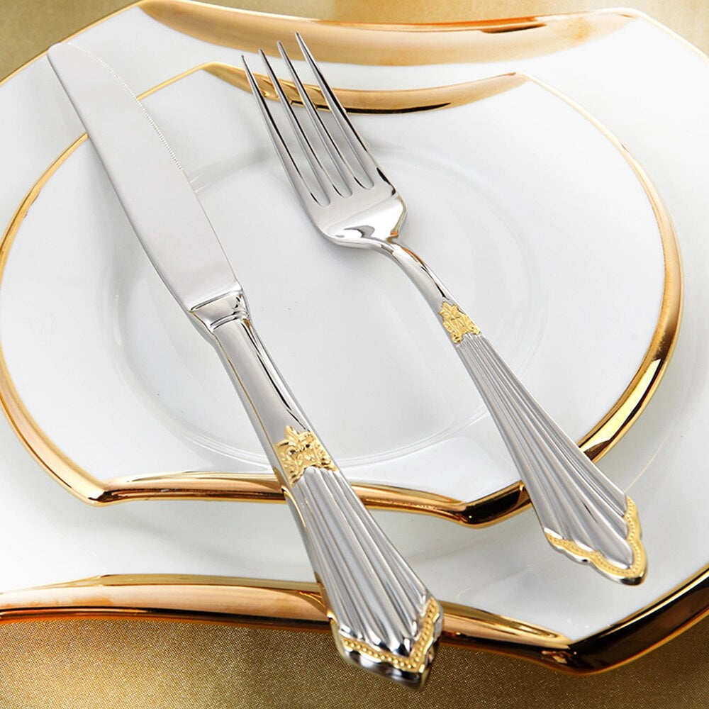 Elegant Luxury Gold and Silver Cutlery Set featuring a fork and table knife displayed on a white plate, arranged on a table with a white tablecloth. Perfect for weddings and luxurious dining settings.