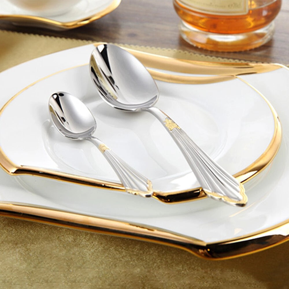 Luxury gold and silver cutlery set elegantly displayed alongside a decorative plate and glassware, showcasing an exquisite table setting ideal for weddings and formal dining.