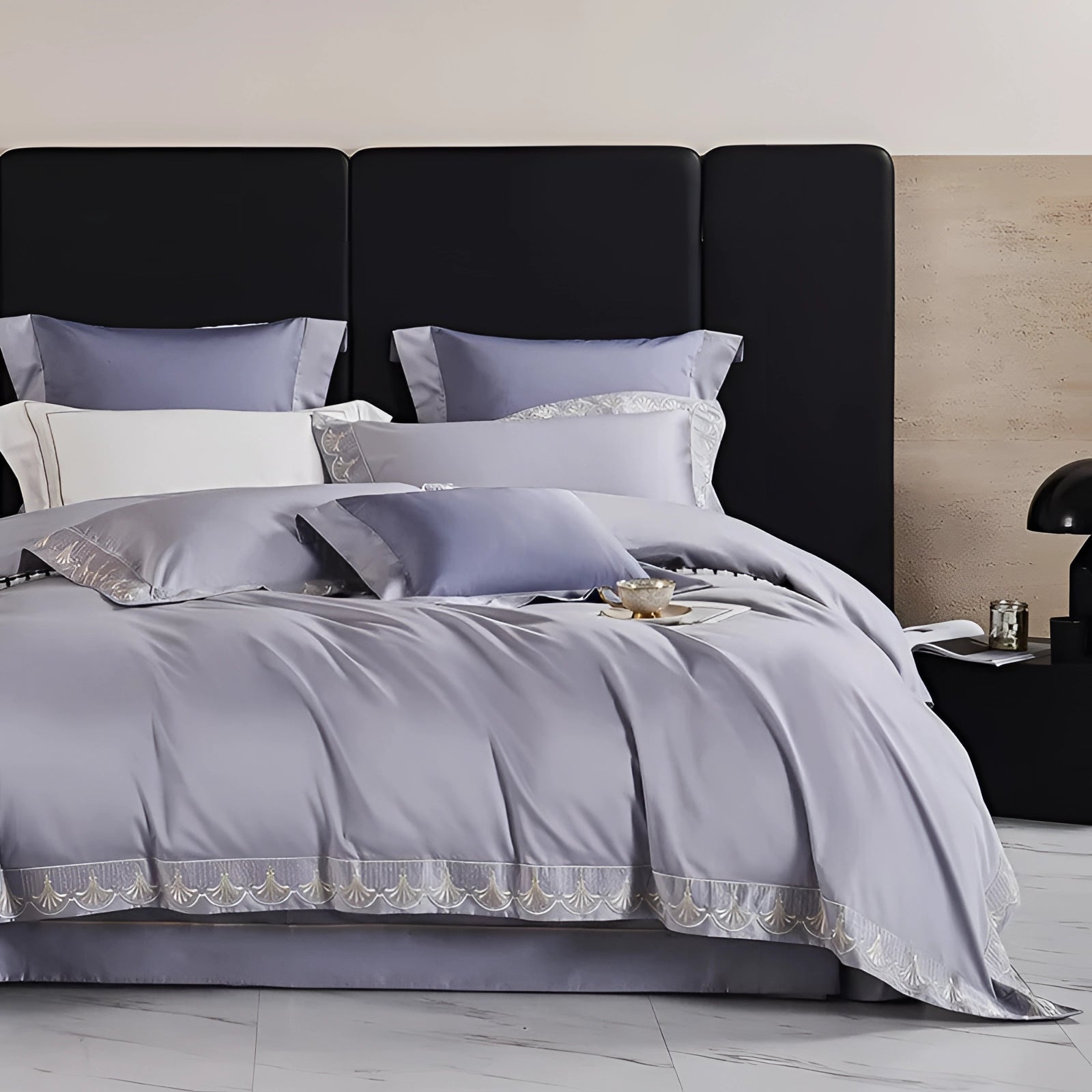 Luxury gray cotton bedding set featuring a silk satin bedspread and matching pillow shams displayed on a bed with a wooden frame, set in a stylishly designed interior.