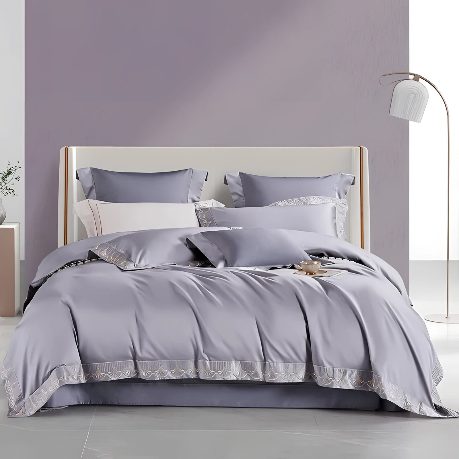 Luxury gray cotton bedding set featuring a silk satin bedspread and matching pillow shams arranged on a wooden bed frame.