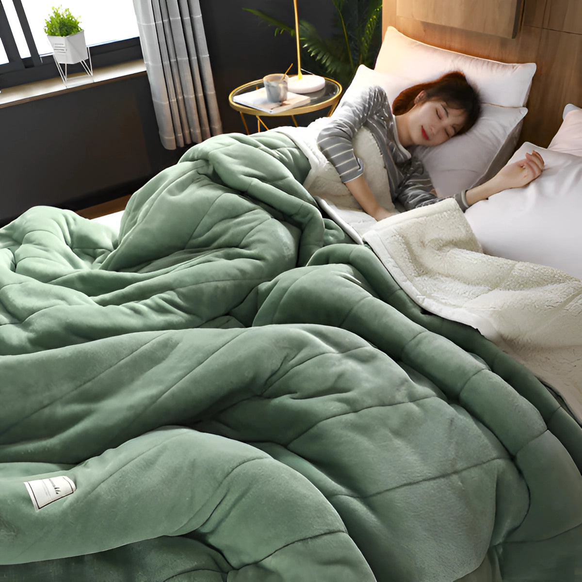 Luxurious gray weighted blanket in a therapeutic and soft fabric, draped over a bed with green linens, in a cozy bedroom setting featuring a lamp and houseplant, size 200x230cm.