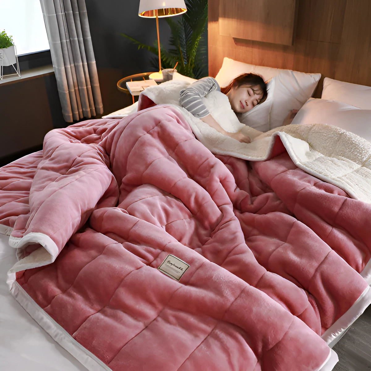 Luxury gray weighted blanket draped over a bed with red linens, set in a well-designed interior featuring a wooden bed frame, decorative pillows, and a nearby houseplant.