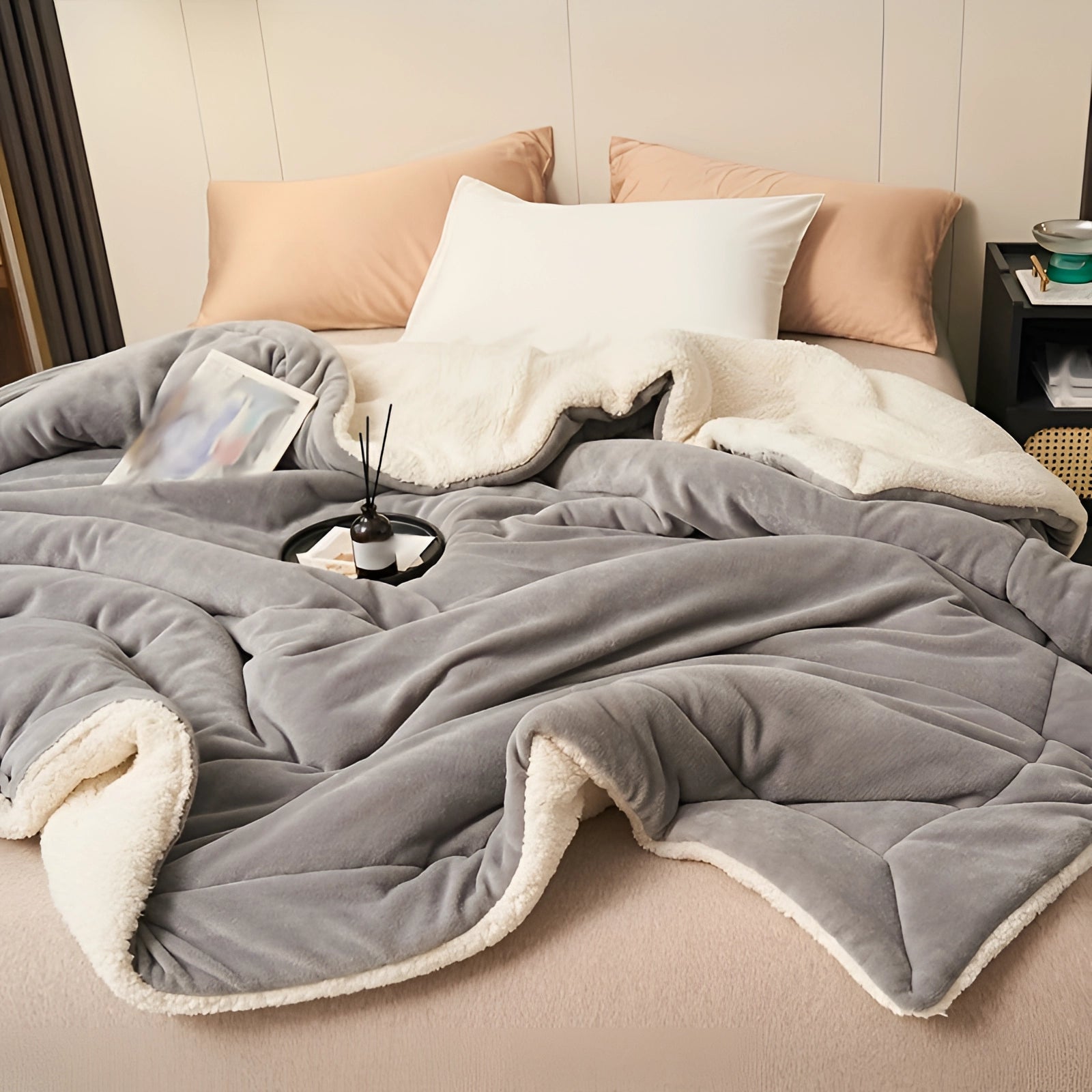 Luxury grey faux fur weighted blanket draped over a plush couch, surrounded by cozy pillows and a stylish bed frame in a warmly lit room.