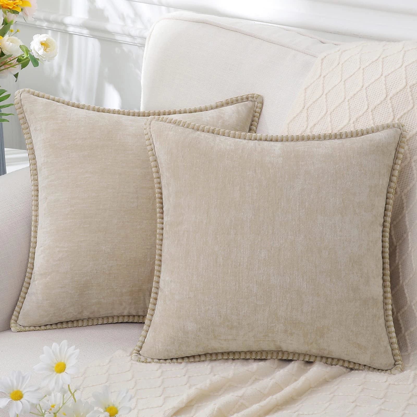 Luxurious beige velvet throw pillows set of four, elegantly arranged on a white couch with floral and plant decor accents in the background, offering a comfortable and stylish touch to home interiors.