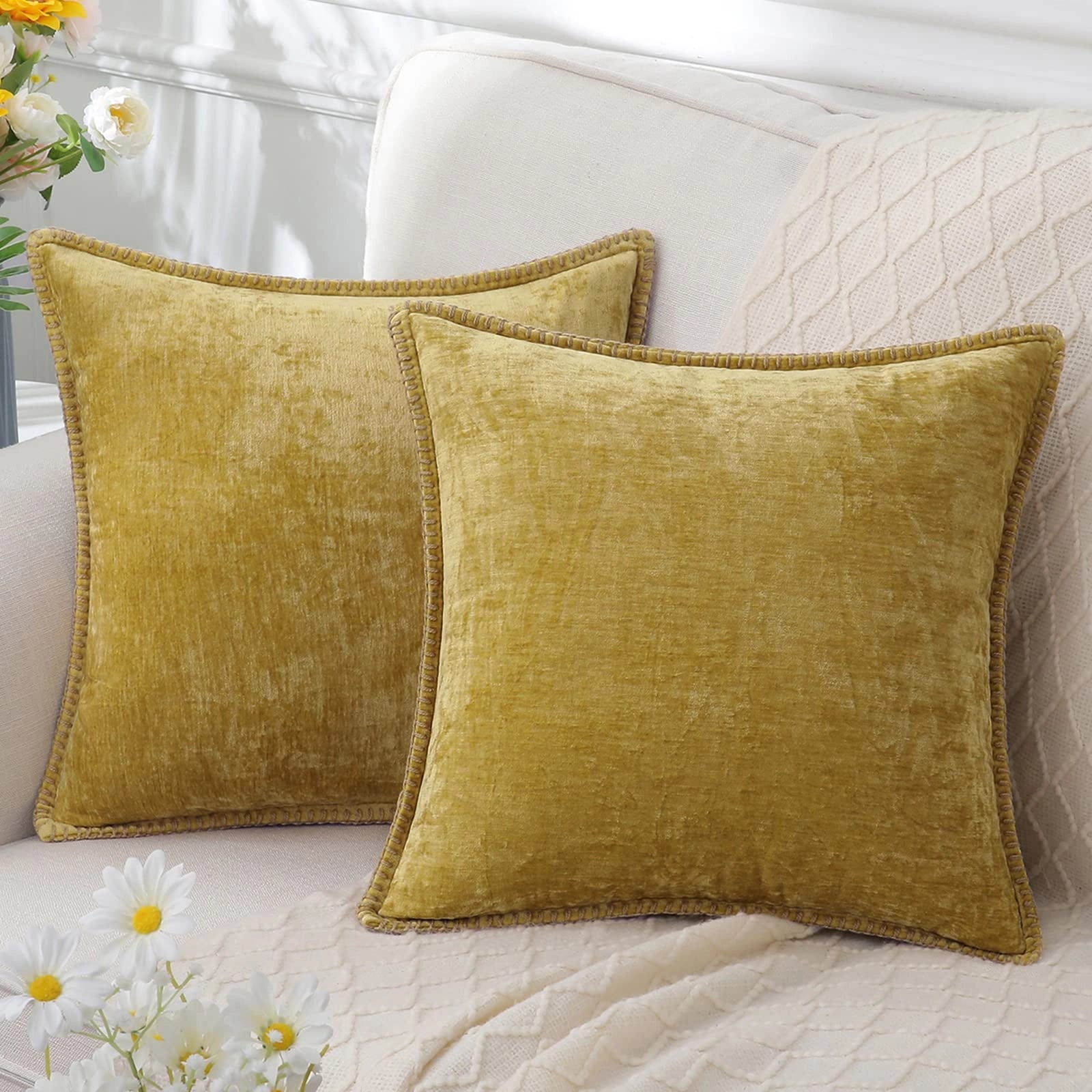 Luxurious grey velvet throw pillows in a set of four with elegant yellow accents, arranged on a beige linen surface. A nearby plant and wooden elements enhance the comfort and style of the decor.