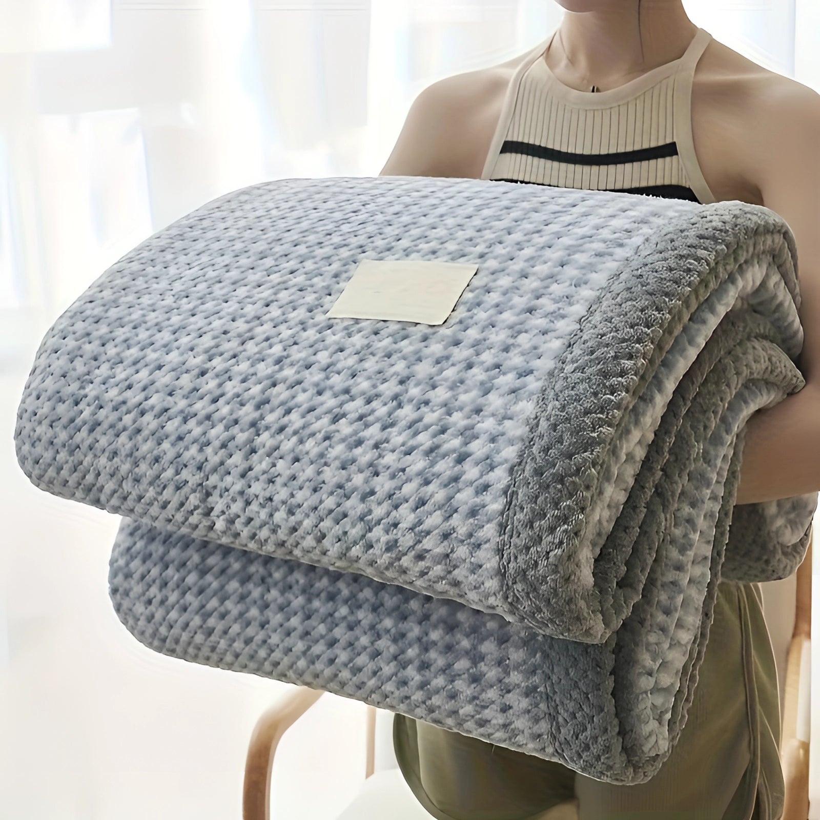 Luxury grey and white checkered fleece blanket draped over a chair, showcasing its cozy and plush texture.