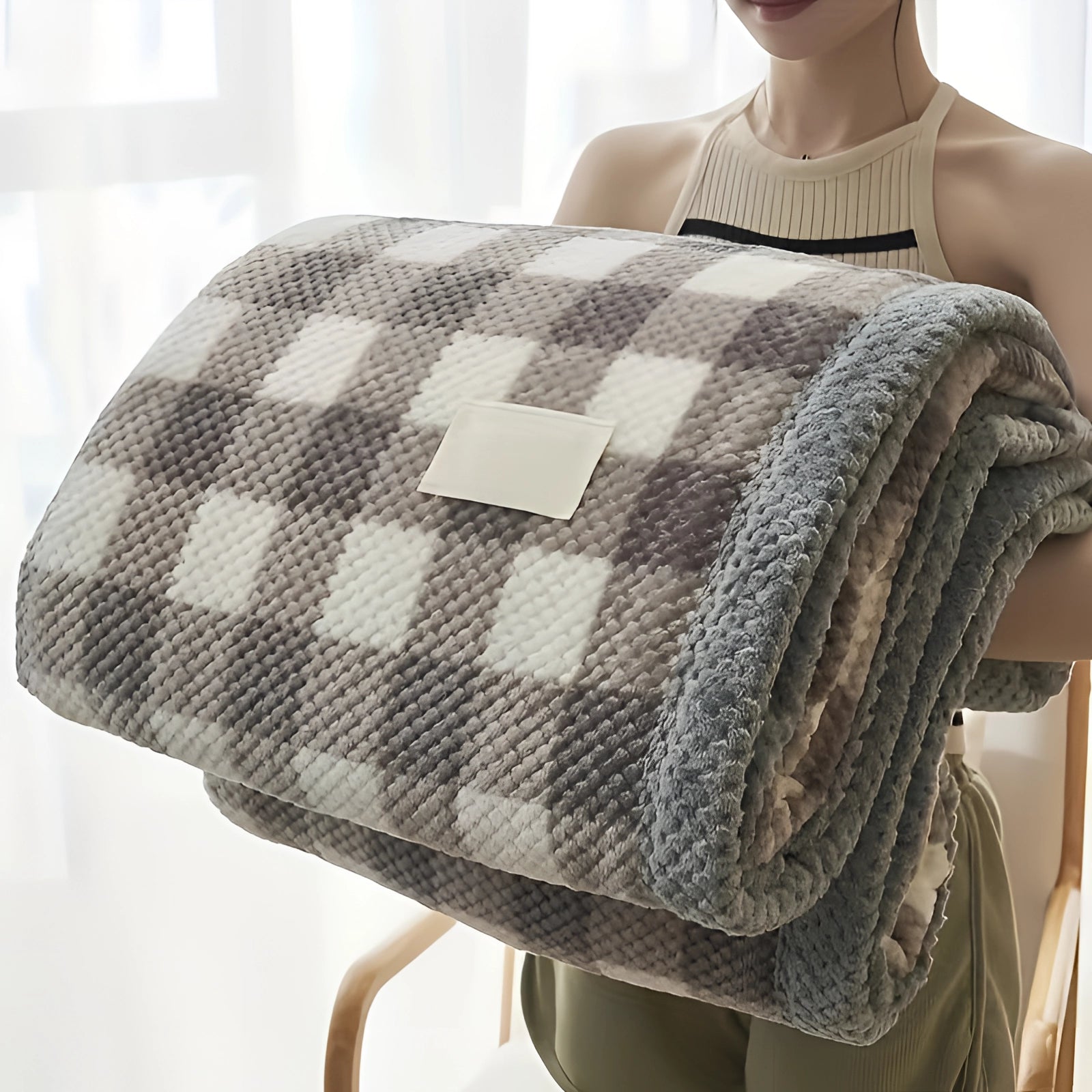 Luxurious grey and white checkered fleece blanket draped over a couch, showcasing its plush and cozy texture.