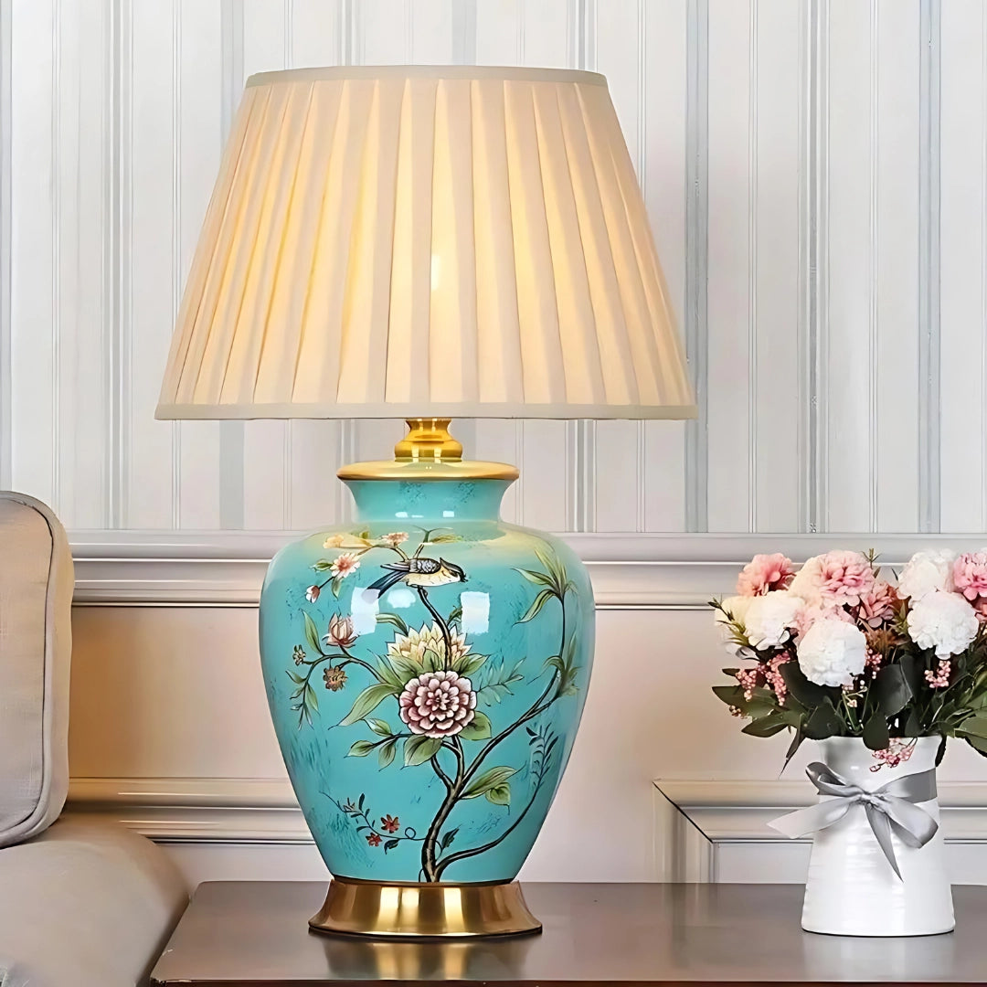 Luxury blue hand-painted ceramic table lamp with gold trim featuring floral designs, displayed in an elegant interior setting.