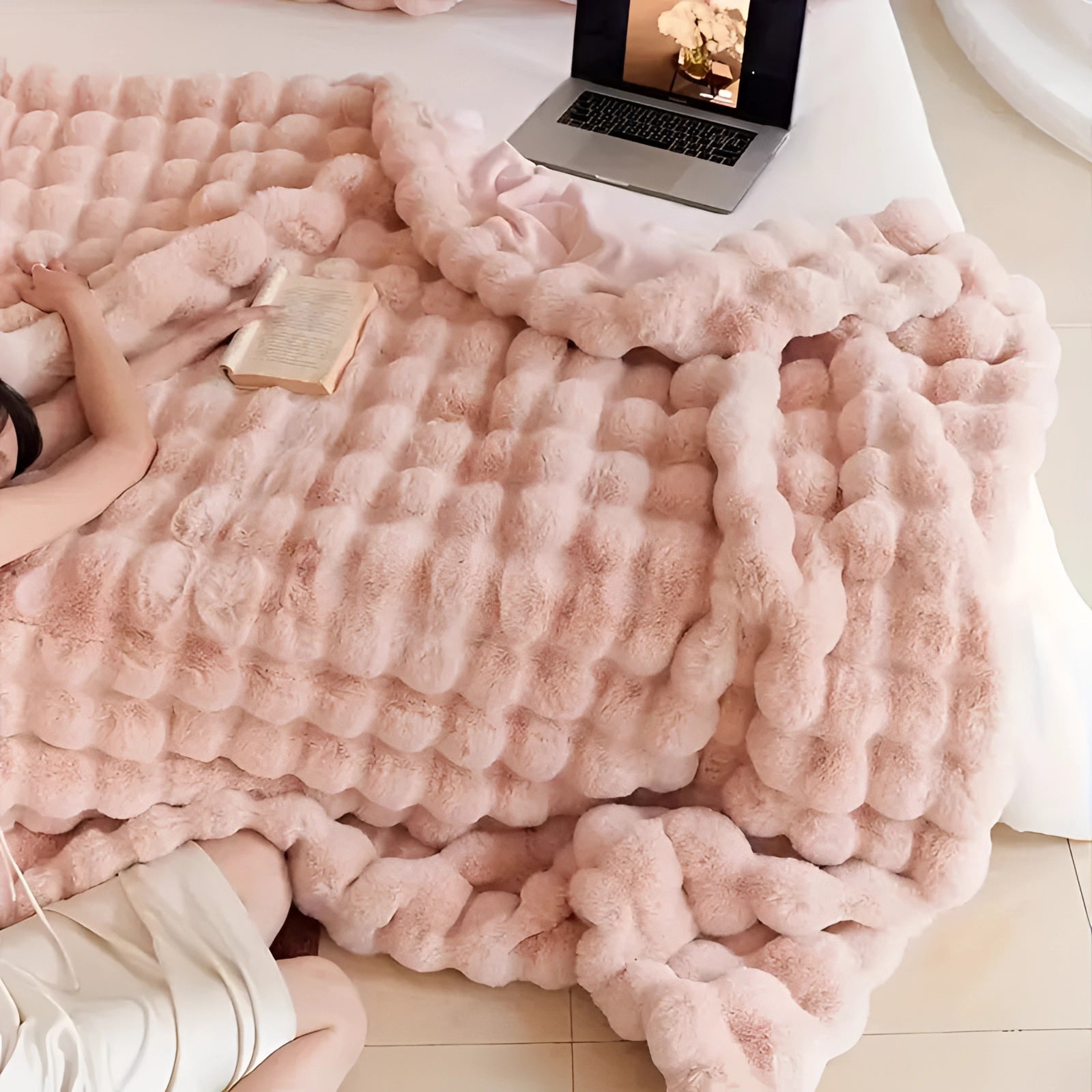 Luxury handmade chunky knit weighted blanket in white draped over a wooden floor, with a laptop nearby, creating a cozy and comforting atmosphere.