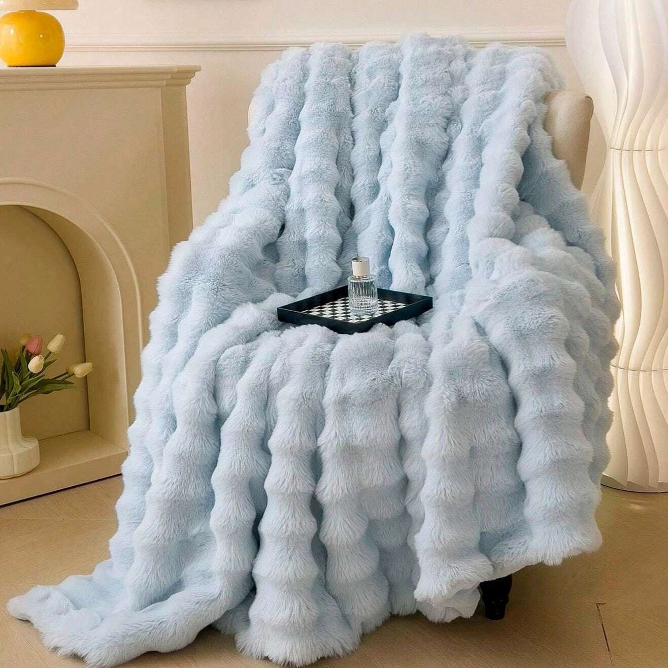 Luxurious handmade chunky knit weighted blanket in a cozy blue color, draped over a flooring surface, providing comfort and style; houseplant and flowerpot visible in the background.