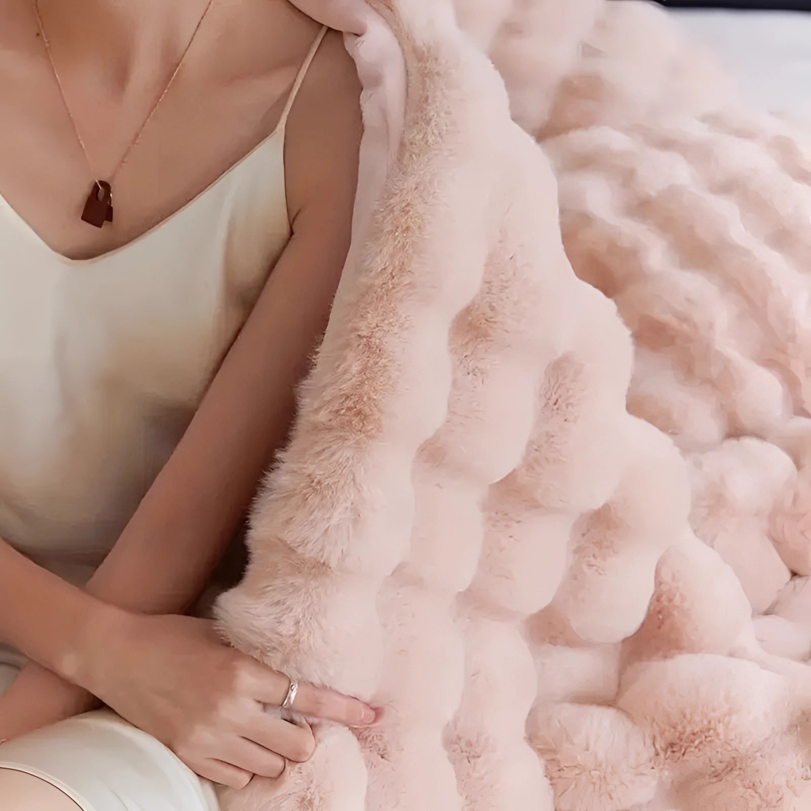 Luxurious handmade chunky knit weighted blanket in white, draped over a person's lap, highlighting the intricate knit pattern with visible hands and arms gently resting on the blanket, showcasing its cozy and soft texture.