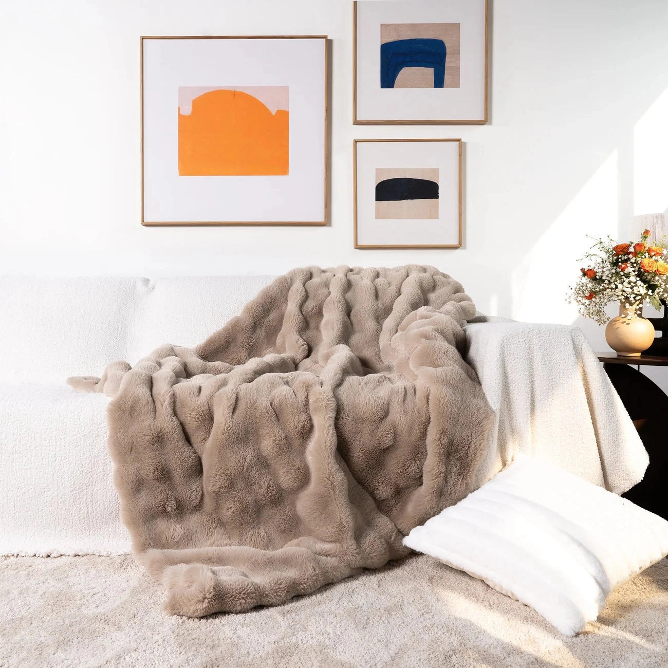 Luxury handmade chunky knit weighted blanket in espresso color, draped over a studio couch in a tastefully designed interior setting, with wood flooring and picture frames enhancing the cozy ambiance. The blanket measures 160x200cm.