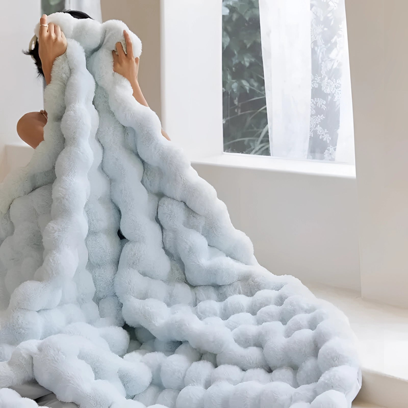 Luxury handmade chunky knit weighted blanket in white draped attractively over a cozy corner, with a window in the background and a minimalist decor setting.