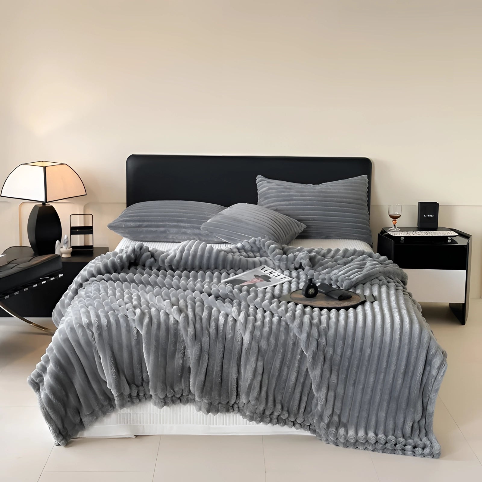 Luxury handmade chunky knit wool blanket in grey draped over a bed with wooden frame in a cozy interior setting, showcasing its oversized and plush texture.