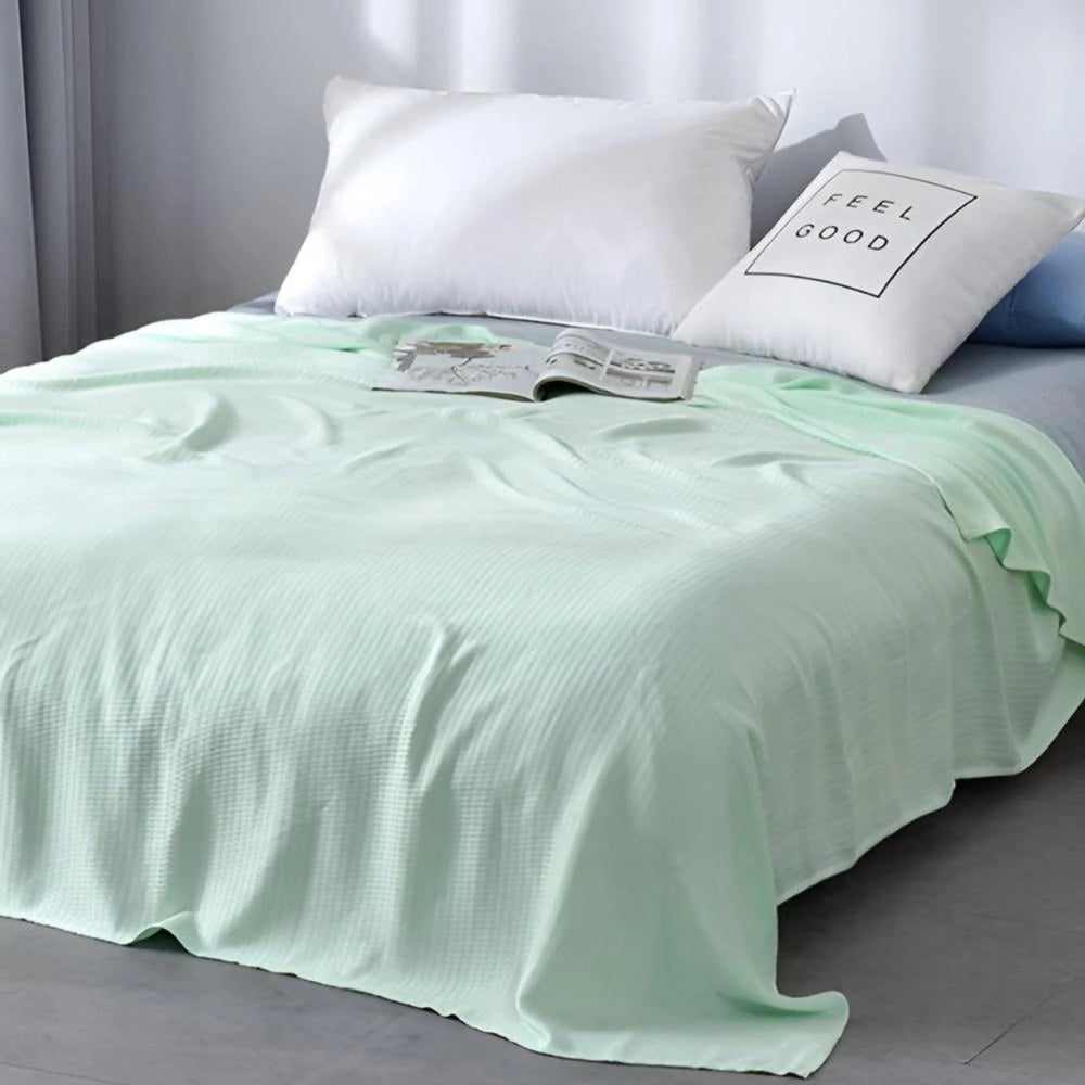 Luxury mint green textured blanket elegantly draped over a bed, showcasing its soft and intricate design. The blanket complements the light and airy setting, adding a touch of elegance to the bedroom decor.