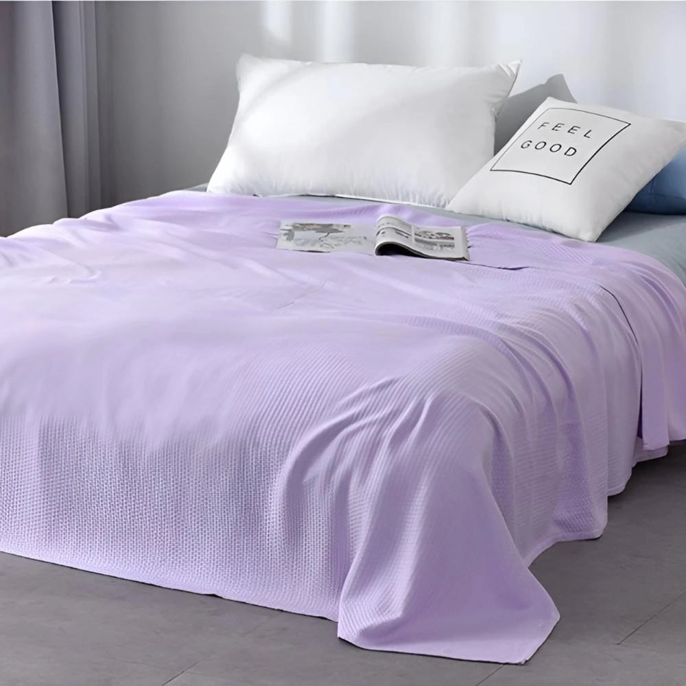 A luxurious mint green textured blanket elegantly draped over a queen-sized bed, featuring purple and white bedding accents, including a bed skirt, pillows, and a stylish bed frame, creating a sophisticated and inviting bedroom atmosphere.