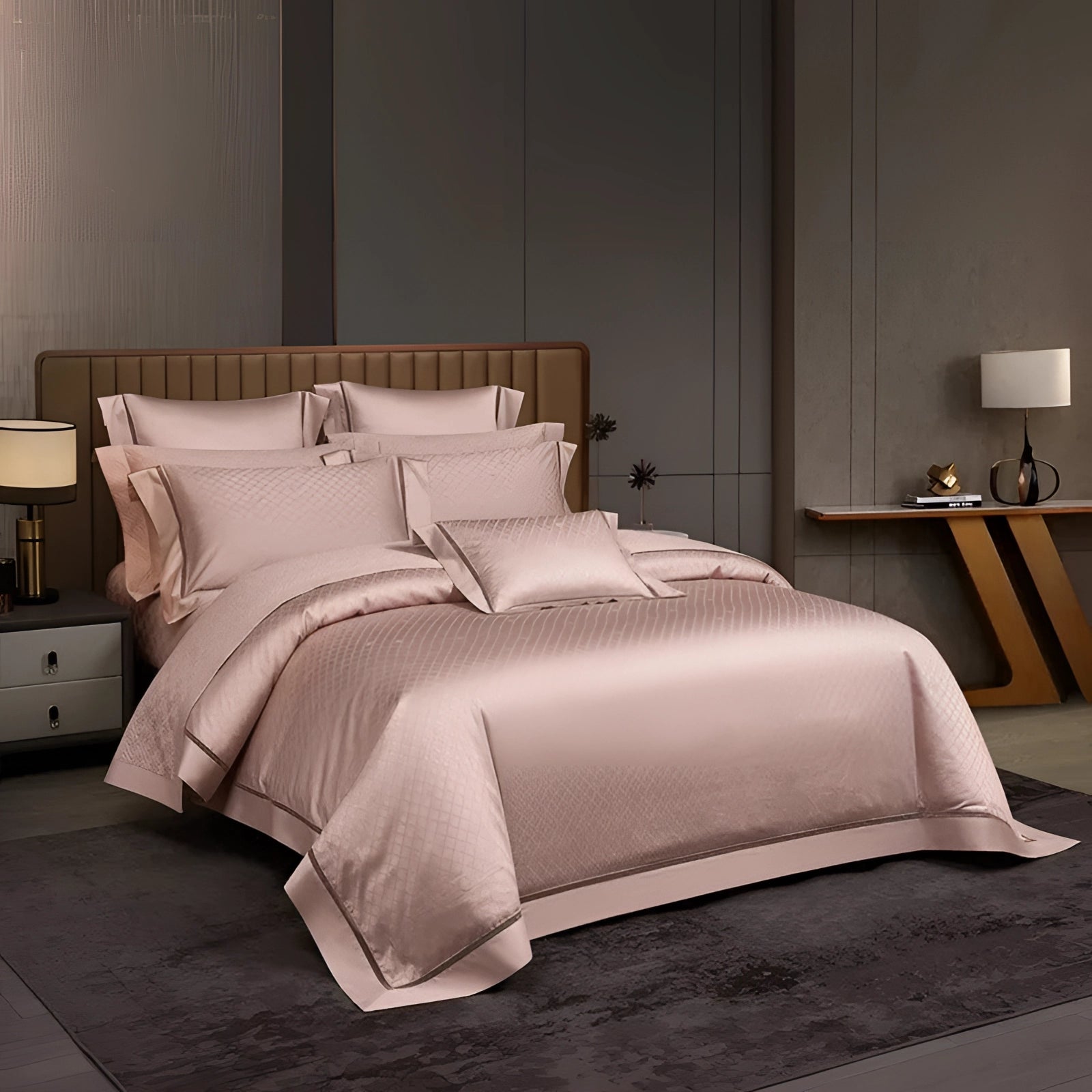 Luxury pink satin bedding set with geometric design, including a duvet and pillowcases, displayed on a neatly made bed with a wooden bed frame, accompanied by soft lighting from a nearby lamp.